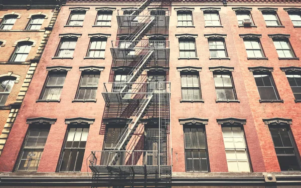 Old building with iron fire escape, color toning applied, New York City, USA.