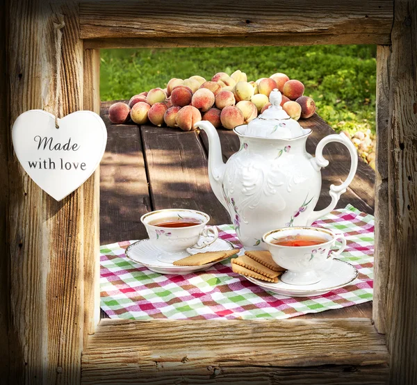 Tee-Set im Garten in Holzrahmen mit Herz. — Stockfoto