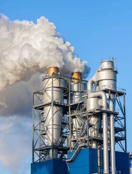 Roken wolken uit een schoorsteen tegen blauwe hemel. — Stockfoto