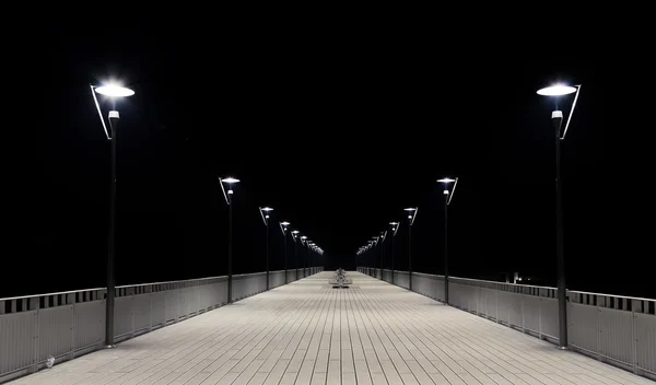 Natt syn på en brygga och lampa trästolpar. — Stockfoto