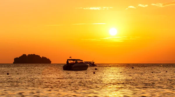 Silhouette einer kleinen Insel und eines kleinen Bootes bei Sonnenuntergang. — Stockfoto