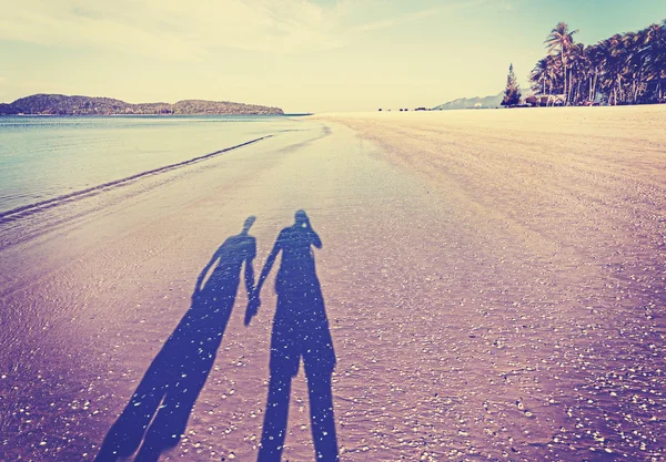 Vintage retro filtered picture of couple's shadow on beach. — Stock Photo, Image