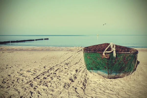 Ретро фильтрованная фотография старой ржавой стальной лодки на пляже . — стоковое фото