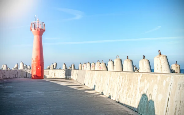 Foto eines Leuchtturms und einer Wellenbrecher aus Betonklötzen. — Stockfoto