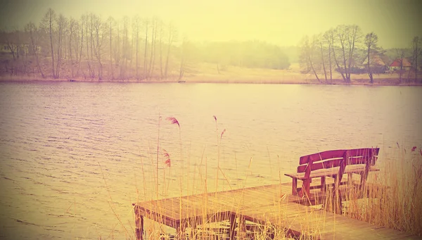 Vintage foto estilizada de un banco de madera en el lago . — Foto de Stock