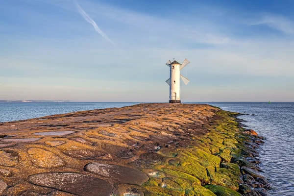 Ostré slunce přes molo a maják v Swinoujscie. — Stock fotografie