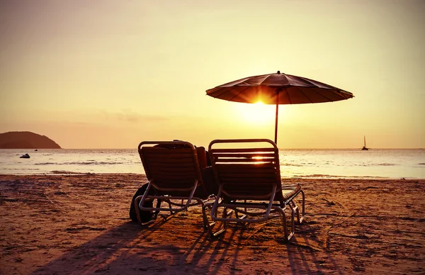 Sillas de playa estilizadas vintage y sombrilla al atardecer . — Foto de Stock