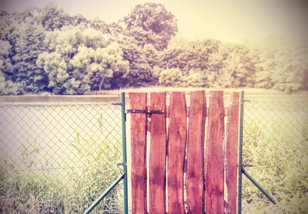 Retro toned wooden garden gate and wire fence. — Zdjęcie stockowe