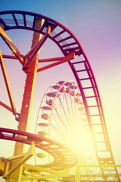 Vintage stylized roller coaster in amusement park at sunset. — Stock fotografie