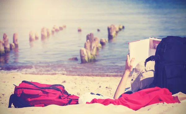 Vintage photo of unrecognizable person reading book on beach. — Stock Photo, Image