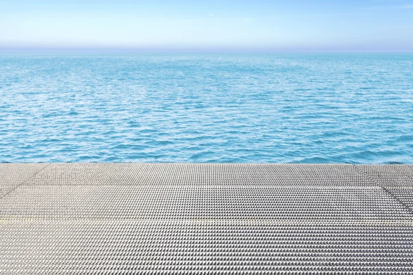 Metall rutnät golv och blått vatten bakgrund. — Stockfoto