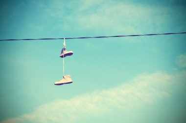 Instagram retro style old shoes hanging on electric cable. clipart