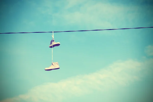 Instagram retro style old shoes hanging on electric cable. — Stock Photo, Image