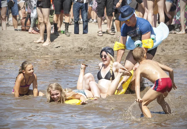 Persone che giocano con i bambini nella piscina di fango . — Foto Stock