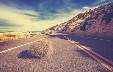 Vintage toned tumbleweed on empty road, travel concept. clipart