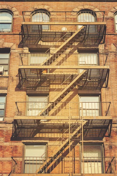Retro style photo of building with fire escape ladders, NYC. — Stock Photo, Image