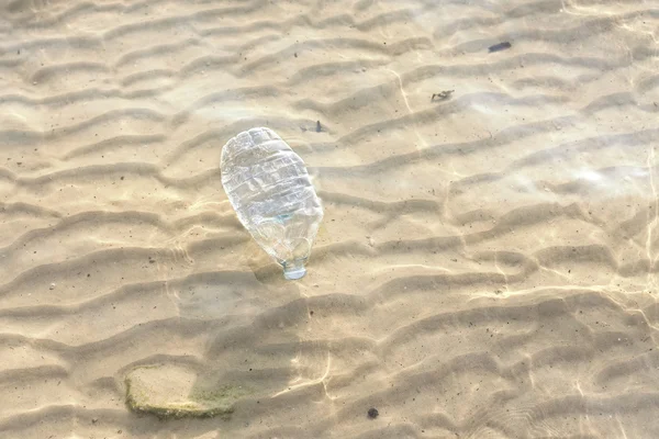 Garrafa de plástico em água do mar rasa . — Fotografia de Stock