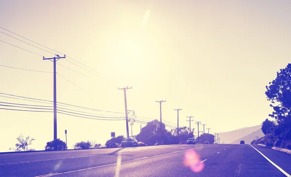 Vintage tonificado carretera al atardecer, imagen contra el sol con lente f —  Fotos de Stock