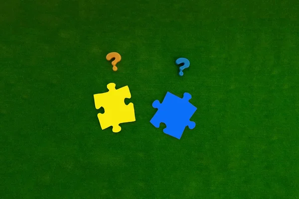 2つの疑問符 緑の背景に青と黄色の2つのパズルピース 共同問題解決 — ストック写真