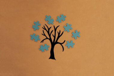 Ağaç, açık kahverengi arka planda yapboz şeklinde taç. Ortak etkileşimin sonucu, iş projesi, takım çalışması..