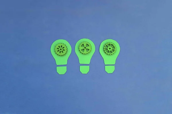 Three electric light bulbs, green gears on a blue background. Creative ideas. Business planning.