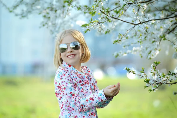 Schöne glückliche kleine Mädchen genießen Geruch in einem blühenden Sprin — Stockfoto