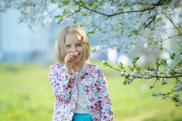 Beautiful happy little girl  enjoying smell in a flowering sprin — Stock Photo, Image