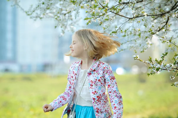 Vacker glad liten flicka njuter av lukt i en blommande perma — Stockfoto