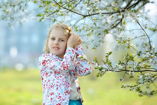 Krásná šťastná holčička těší vůni kvetoucích ružina — Stock fotografie