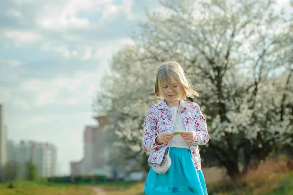 Krásná šťastná holčička těší vůni kvetoucích ružina — Stock fotografie