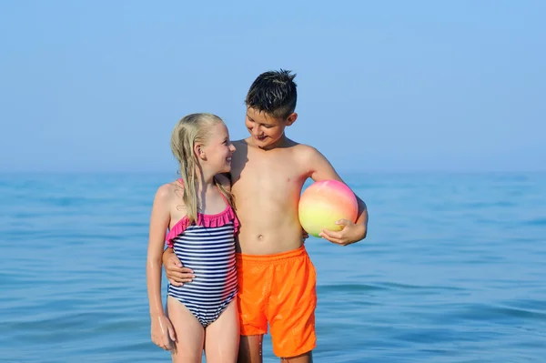 Petit garçon et petite fille jouant au ballon dans une belle mer tropicale — Photo