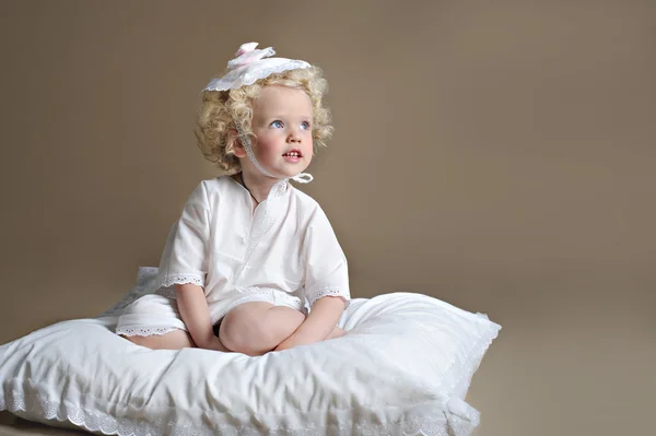 Dulce niña sentada en una almohada — Foto de Stock