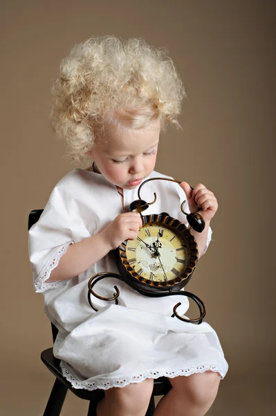 Portrait of a little girl in pajamas with a clock — Stock Photo, Image
