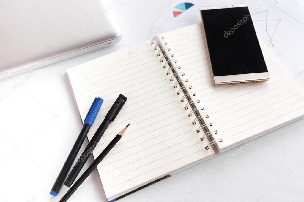 Blank note book with pencil pen laptop and smartphone concept an