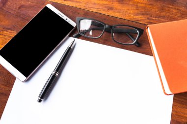 Boş kağıt kalem ve ahşap masa üstünde smartphone ile