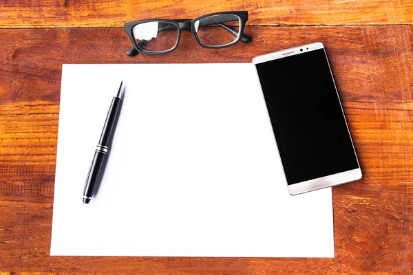 Papier blanc avec stylo et smartphone sur table en bois — Photo