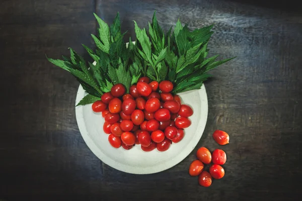 Tomates pequenos e verdura verde em backgr de madeira preto rústico — Fotografia de Stock