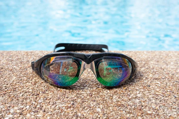 Glasses for swimming on a cement floor with small stone near swi — Stock Photo, Image