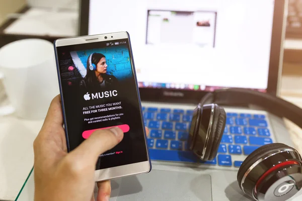 Мужчина держит в руке снимок экрана музыкального приложения Apple, показывающего на Андро Стоковая Картинка