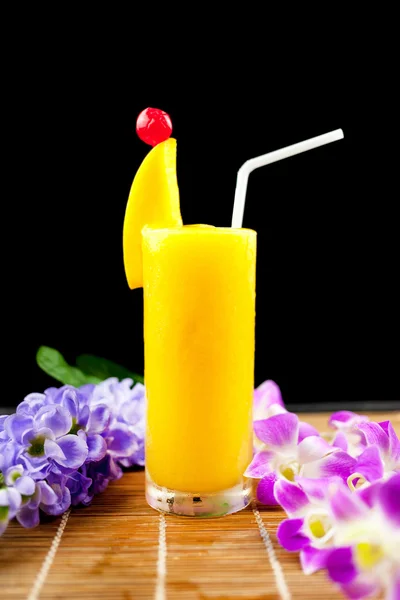 Mango juice and fruit on glass near flower isolation black backg — Stock Photo, Image