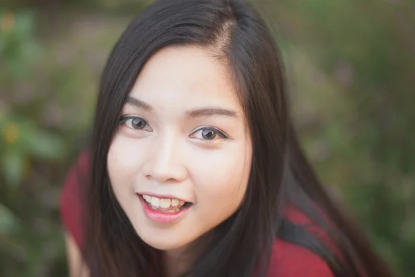 Hermosa chica está sonriendo con traje rojo en el parque natural —  Fotos de Stock