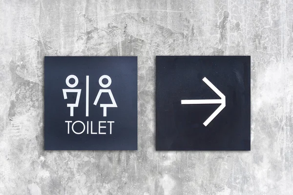 Унисекс туалет или Туалет со стрелкой на бетонной стене — стоковое фото