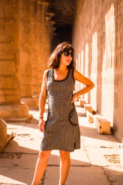 Aswan şehrinin yakınlarındaki Edfu Tapınağı 'nın sütunlarında yürüyen genç bir esmer. Mısır, Nil 'in batı kıyısı Edfu şehrinde, Greko-Romen inşaatı, Horus' a adanmıştır.