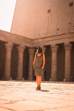 Aswan 'da güneş doğarken Edfu Tapınağı' nı ziyaret eden şapkalı genç bir turist. Mısır, sabahleyin boş tapınakla.