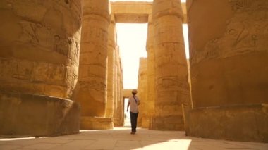 Karnak tapınağında yürüyen genç bir kadın ve onun güzel hiyeroglif sütunları, Amun 'un büyük mabedi. Mısır