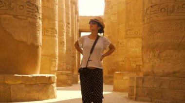 Amun 'un büyük tapınağı Karnak Tapınağı' nın hiyeroglif sütunlarında gezinen genç bir kadın. Mısır