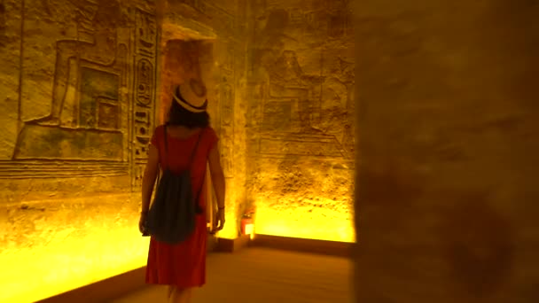 ヌビアのナセル湖の隣にあるエジプト南部のアブ シンベルの神殿の中に照らされた象形文字を見ている若い女性 ファラオラムセス2世の神殿 4Kビデオ — ストック動画