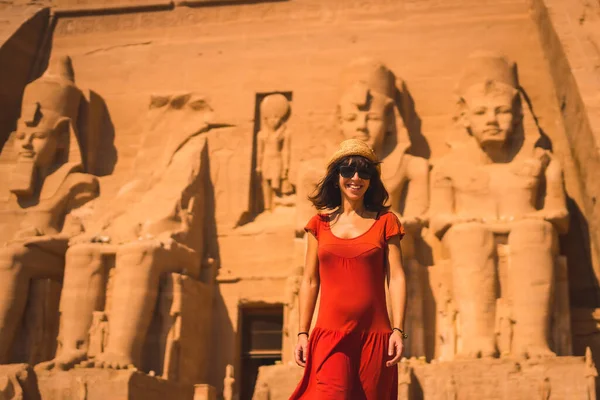 A young tourist in a red dress leaving the Abu Simbel Temple in southern Egypt in Nubia next to Lake Nasser. Temple of Pharaoh Ramses II