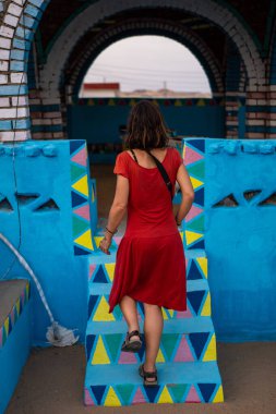 Genç bir turist, Nil nehri boyunca ve Aswan yakınlarındaki Nubian köyünde geleneksel mavi bir evi ziyaret ediyor. Mısır