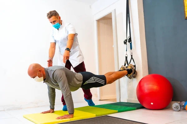 Maszkos Fizioterapeuta Egy Beteg Fekvőtámaszozik Lábával Levegőben Fizioterápia Coronavirus Pandémia — Stock Fotó